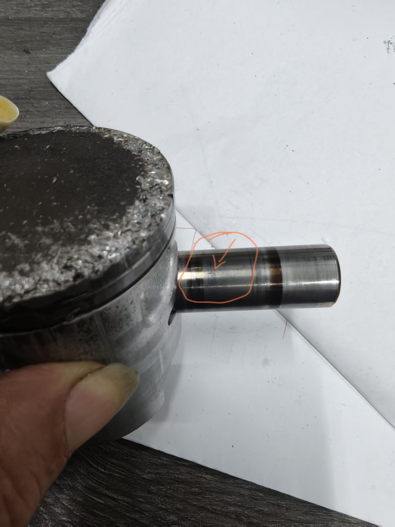Suspected surface defect location on a piston pin, marked with an orange outline and arrow